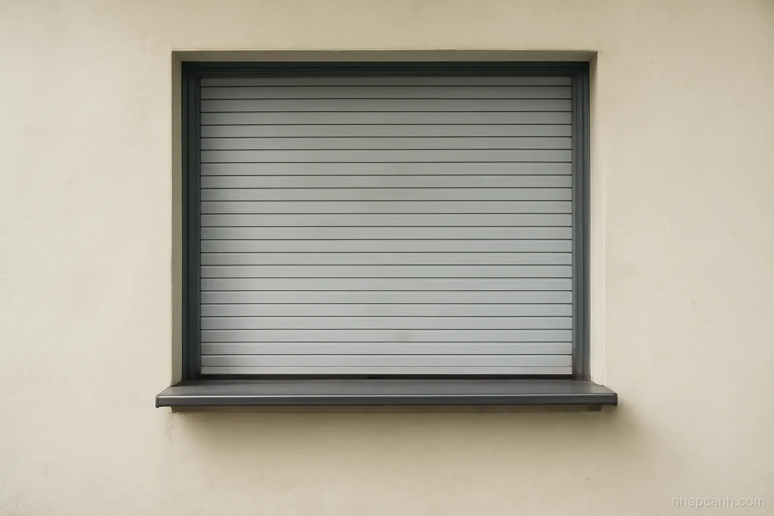 an empty government service window with a closed shutter and a small counter ledge, plain wall, even daylight, no signage